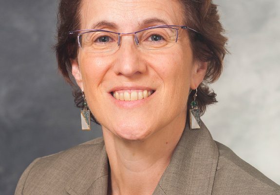 A woman with short brown hair wearing glasses and a tan blazer