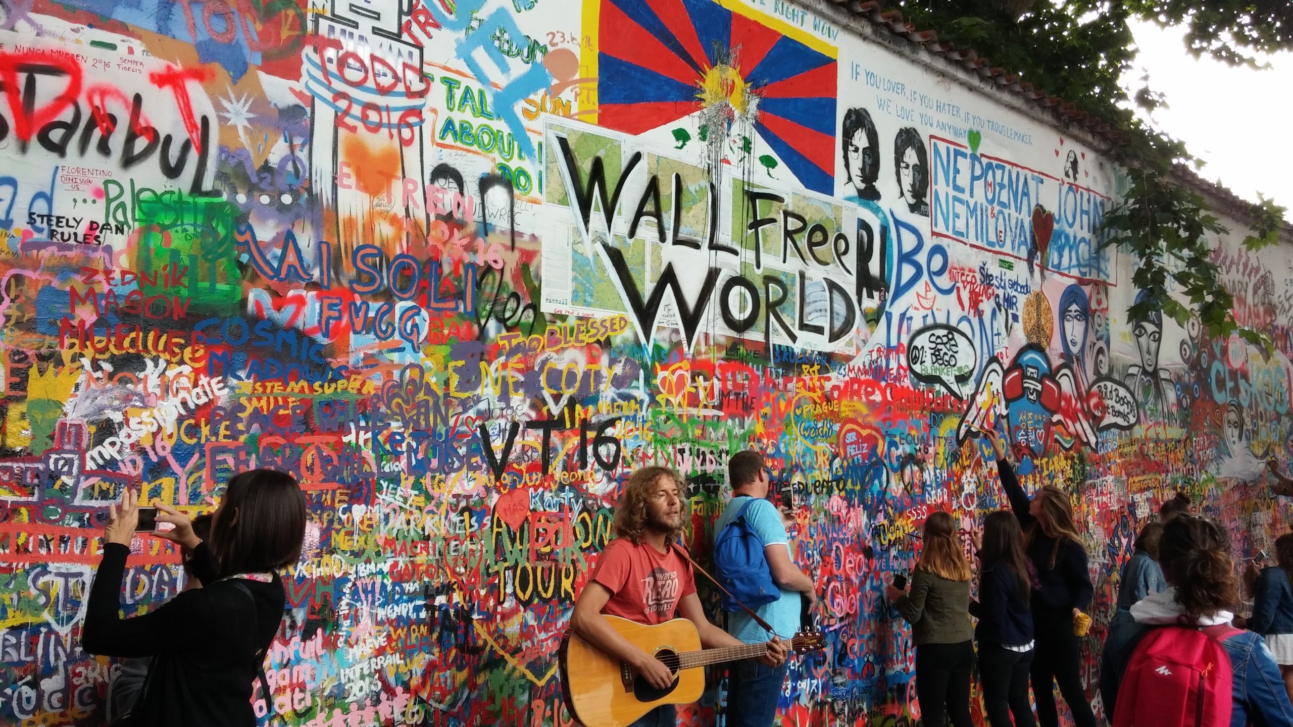 This image captures a vibrant scene at the John Lennon Wall in Prague, Czech Republic.