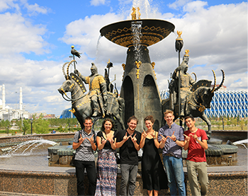 This photo shows a fountain located in front of the National Museum of the Republic of Kazakhstan in Astana. UW-Madison Russian Flagship students stand in front of it holding up the W sign. 