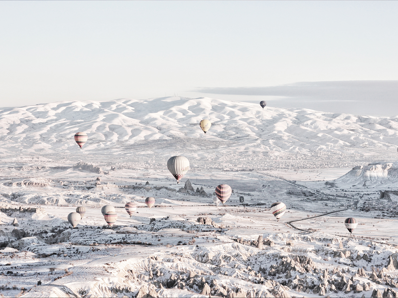Hot air balloons fly over a field in Turkey.