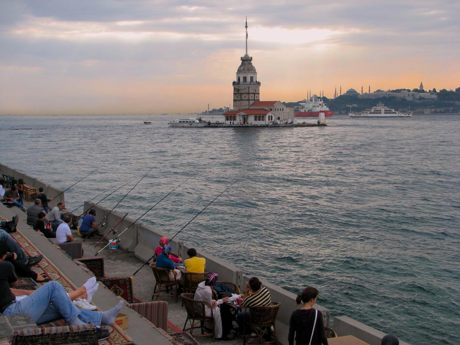 A group of people fish on the docks of a bay in Turkey.