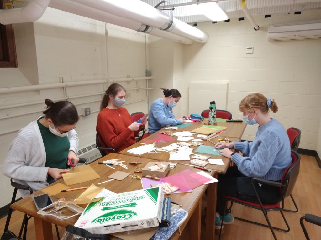 A photo featuring residents of Stockwerk Deutsch doing paper crafts at a table.