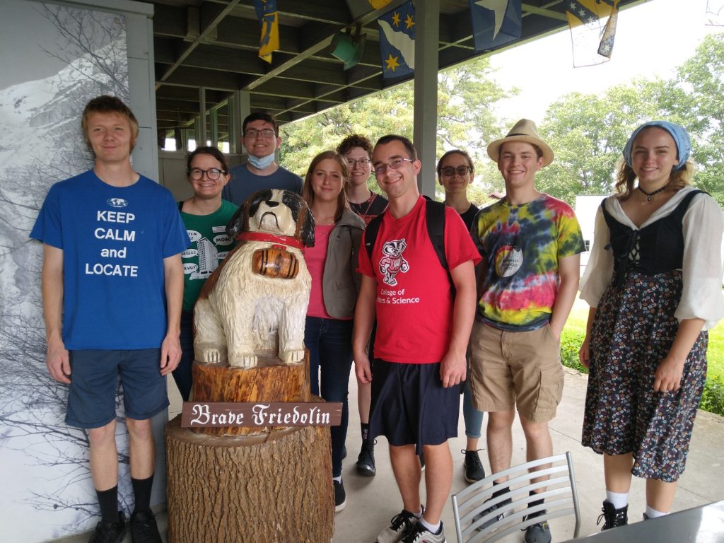A photo featuring residents of Stockwerk Deutsch next to a statue of Brave Friedholm.