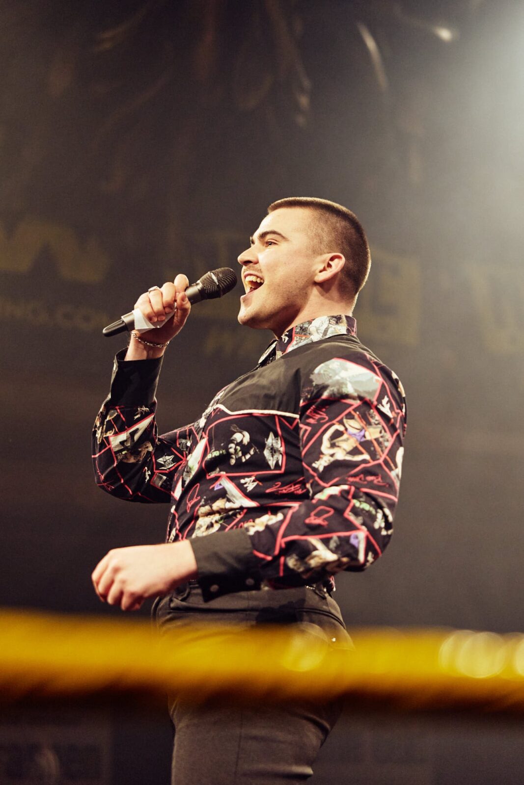 Image of Aaron Hathaway announcing with a microphone. 
