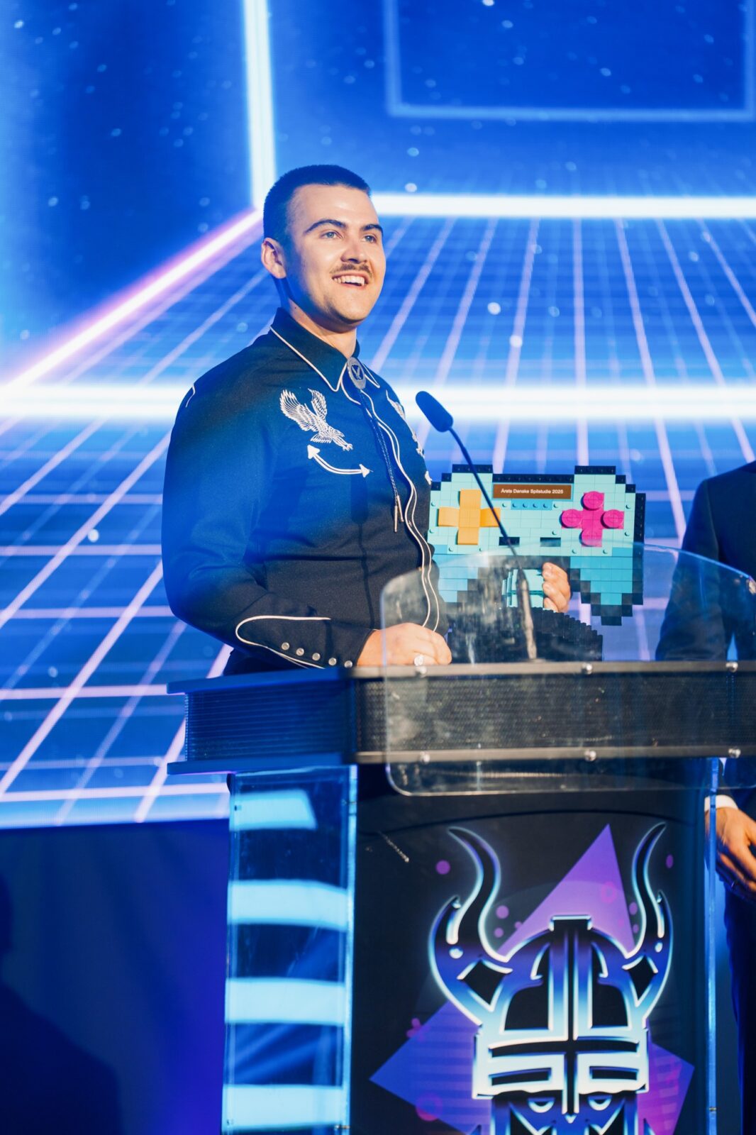 Image of Aaron Hathaway speaking at a video game awards show. 