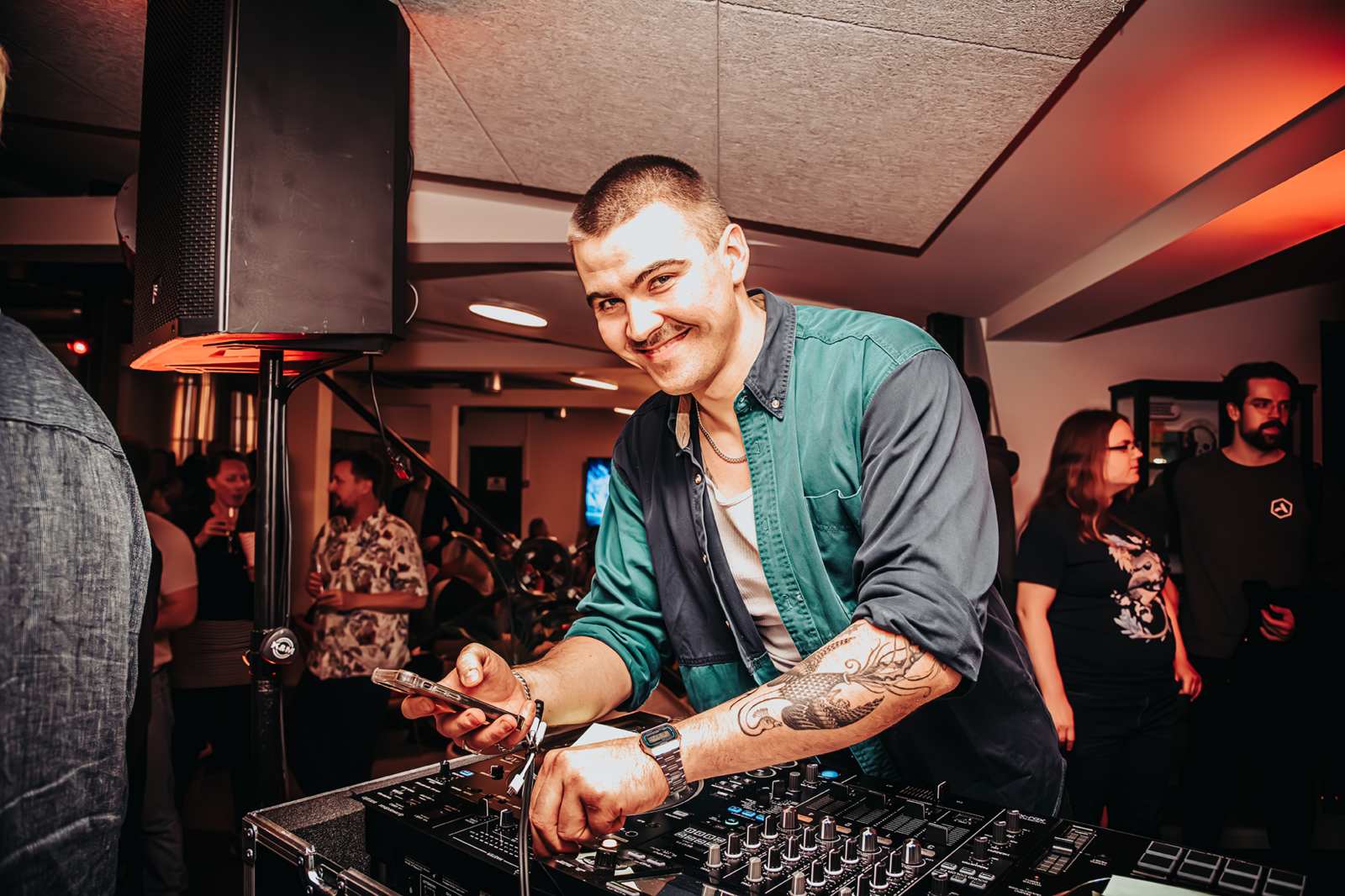Image of Aaron Hathaway, indoors, using a synthesizer or DJing equipment.